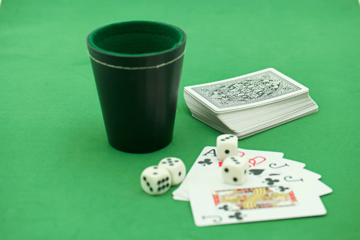 Dice and playing cards arranged on a green felt surface.
