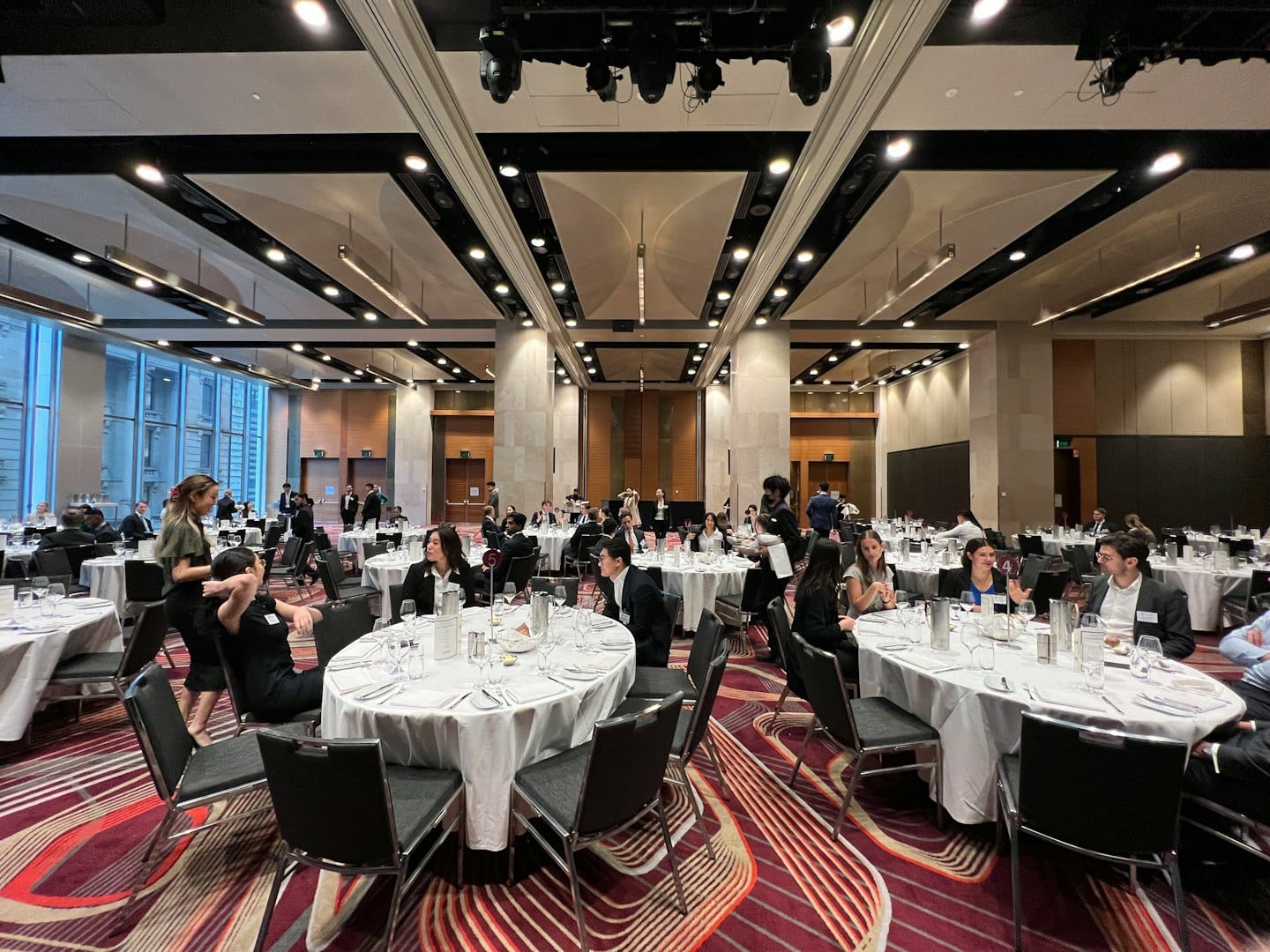 Professionals networking at tables in a modern conference hall.