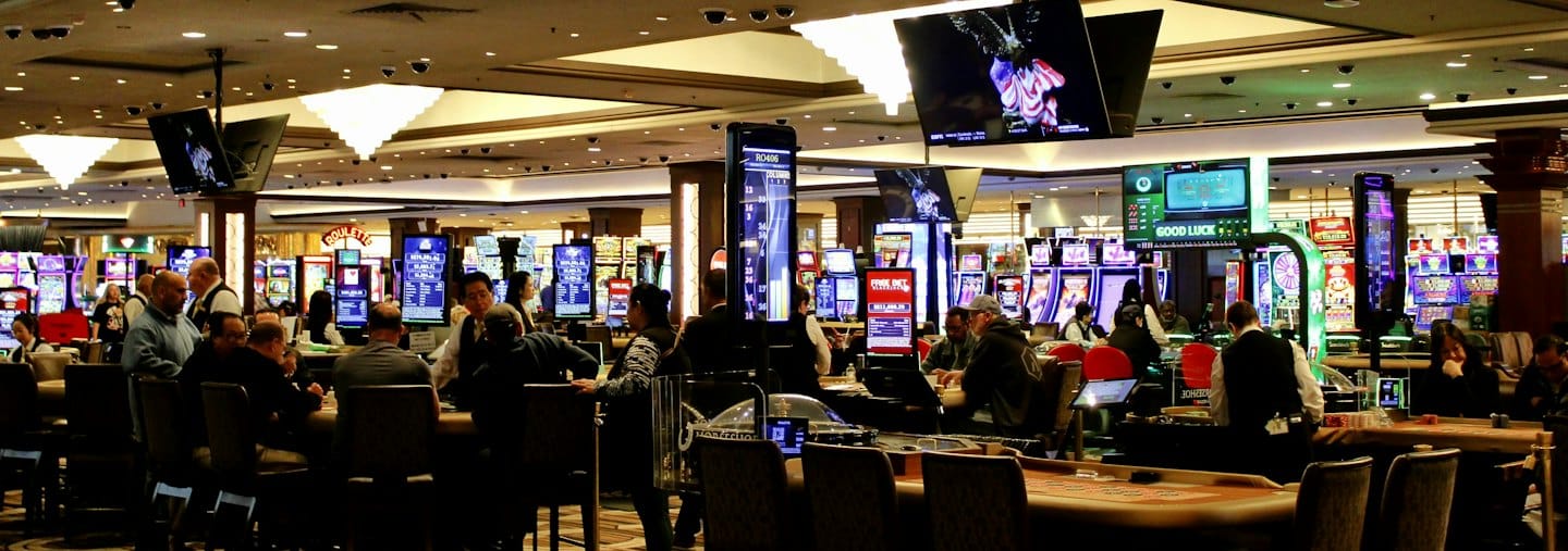 People playing table games and slot machines on a busy casino floor.
