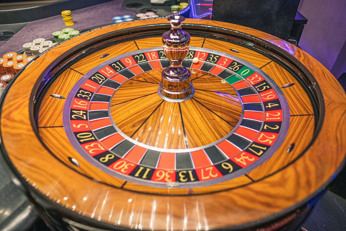 Wooden roulette wheel with white ball in a numbered slot.
