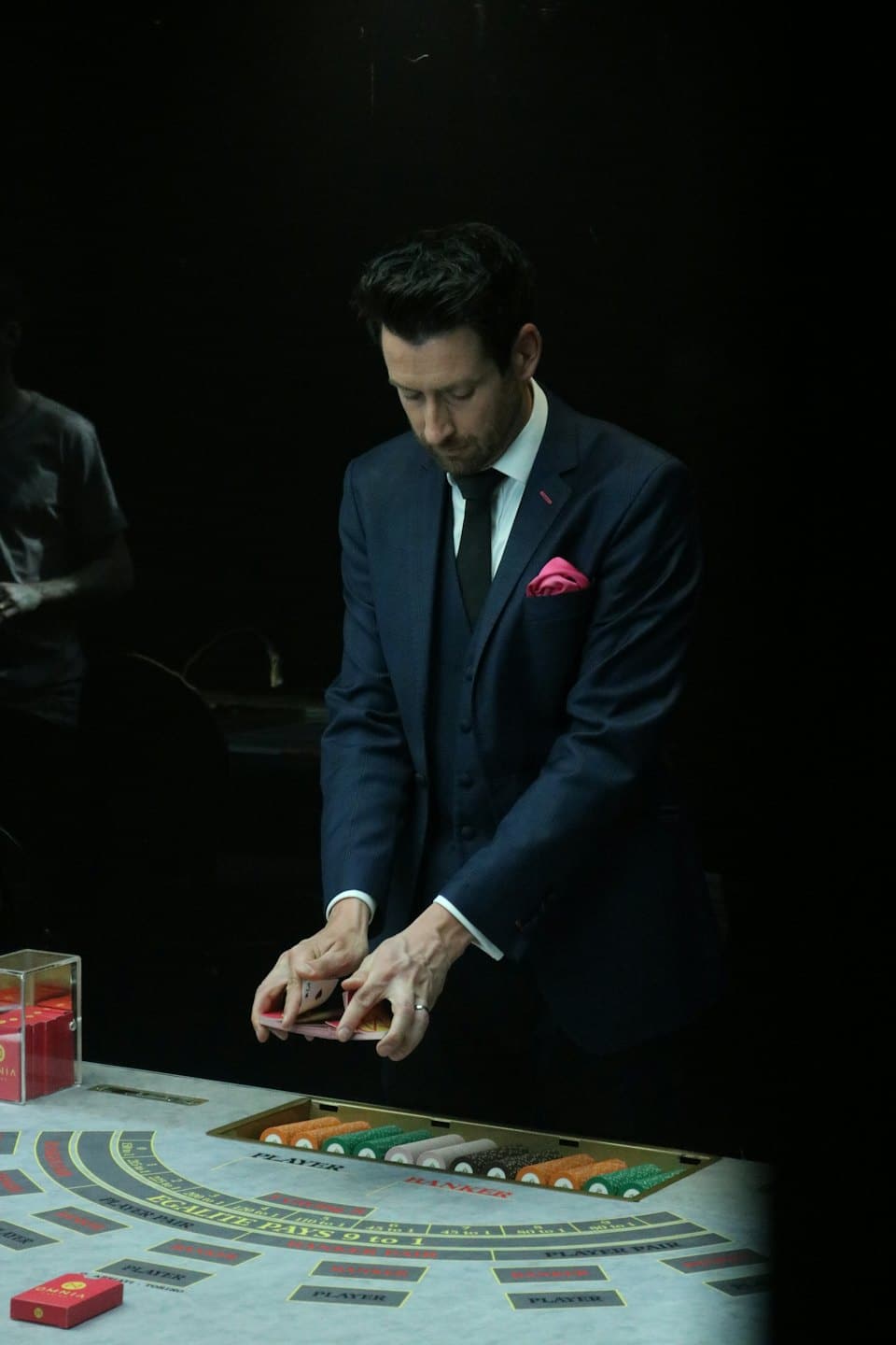 Casino dealer shuffles cards at a baccarat table.